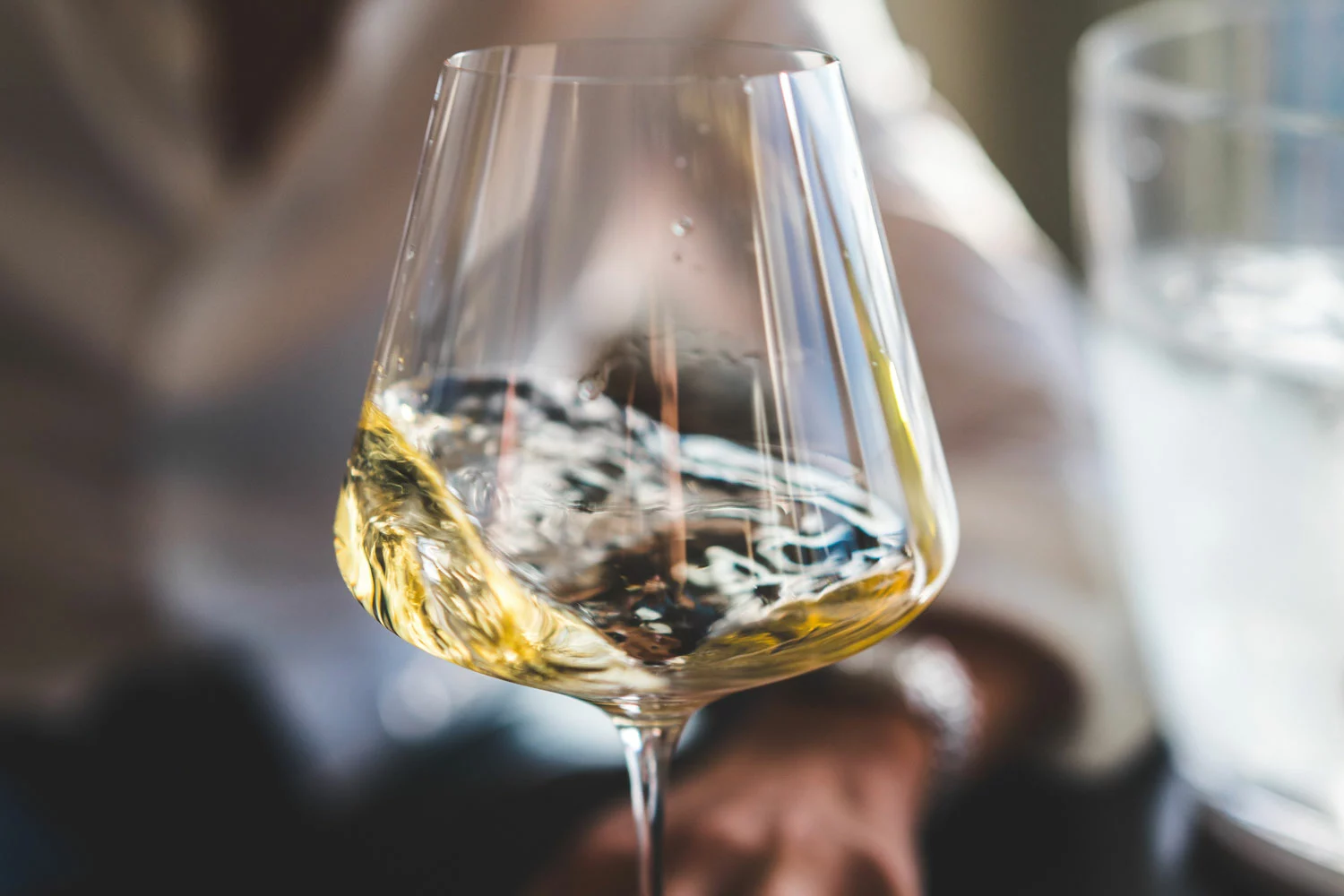 A person is holding a glass of white wine.
