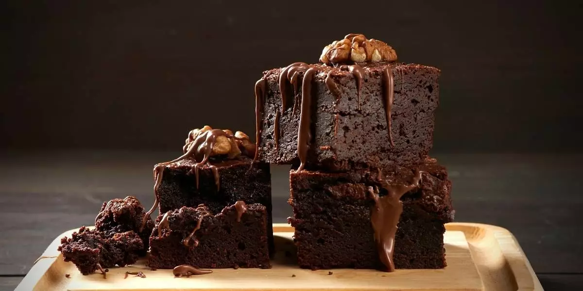 A stack of chocolate brownies on a wooden cutting board.