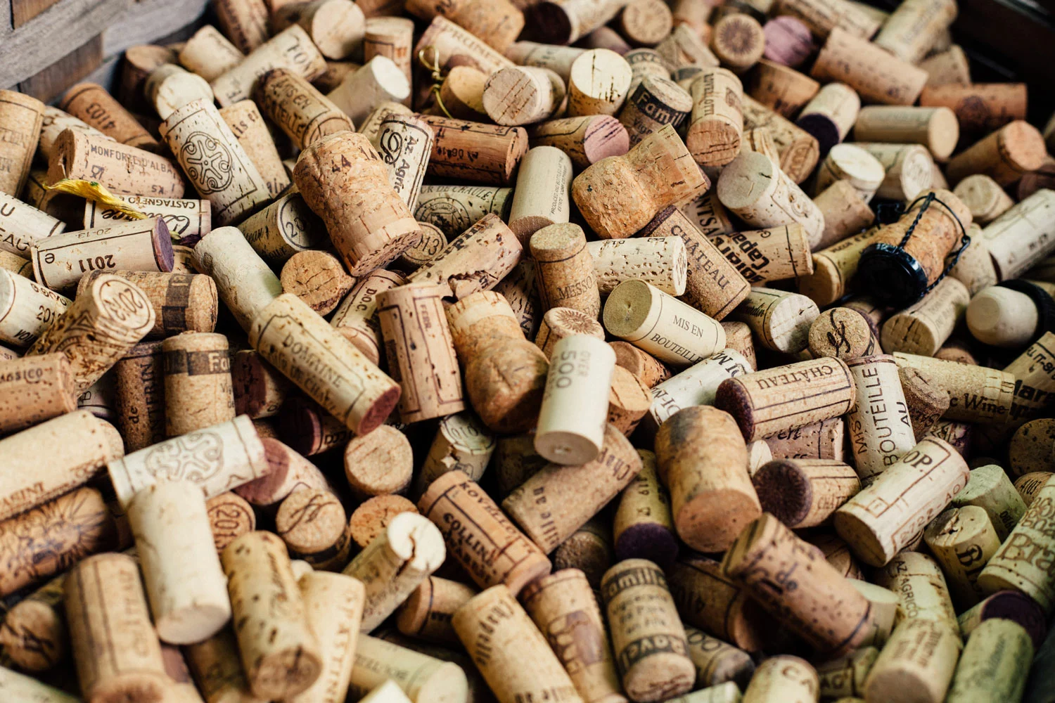 A pile of wine corks in a wooden crate.