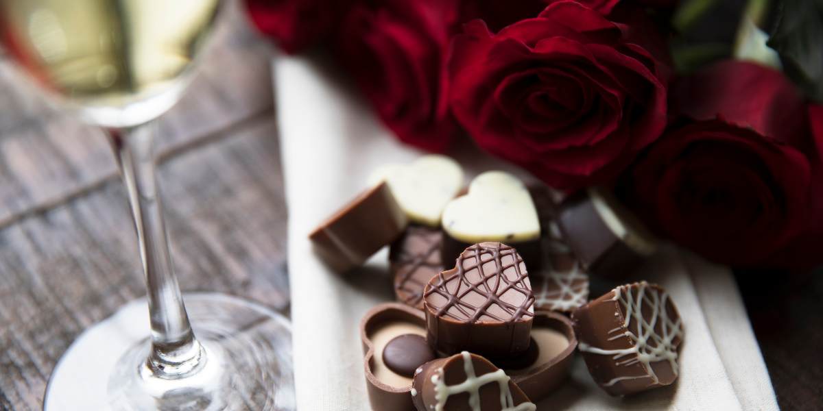 Chocolates and roses on a plate next to a glass of champagne.