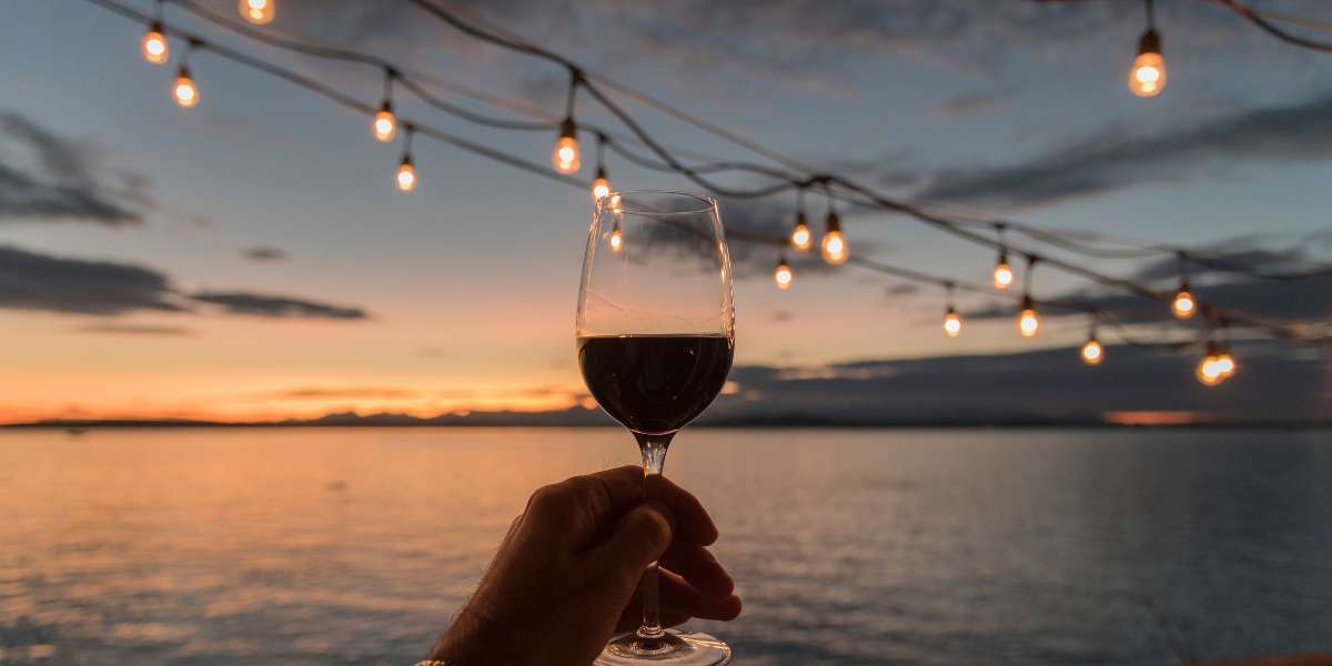 A hand holding a glass of wine at sunset.
